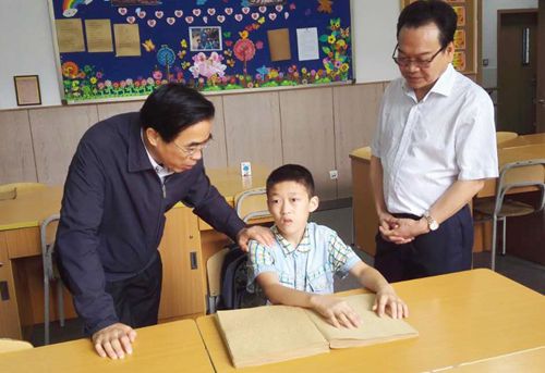 图为在重庆盲校了解盲生学习使用国家通用盲文情况