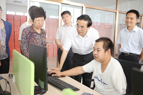 图为程凯副理事长与通过数字化扫盲实现就业的残疾人交谈