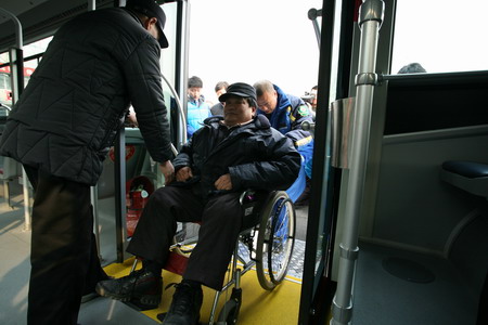 图为吕世明、丁向阳等与会领导和残疾人一起乘坐无障碍公交车