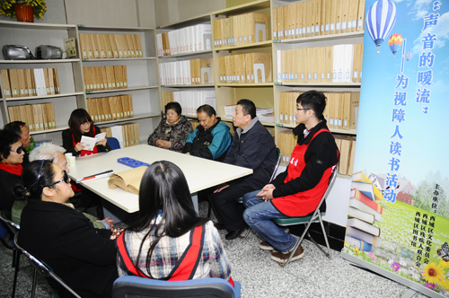 图为 大学生志愿者为盲人朋友阅读《走进台湾》
