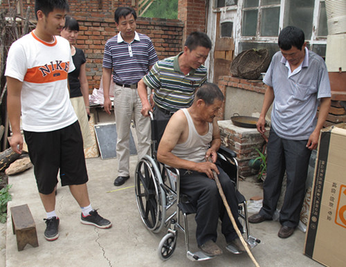 图片为：市辅具中心党团员代表为残疾人送上轮椅