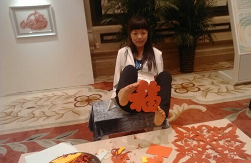 图为残疾女孩夏虹展示自己的剪纸作品“福”字
