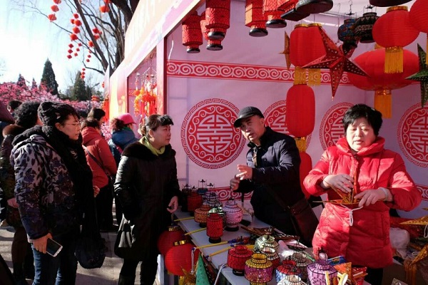 图为从艳梅同志在残疾人公益摊位了解售卖情况